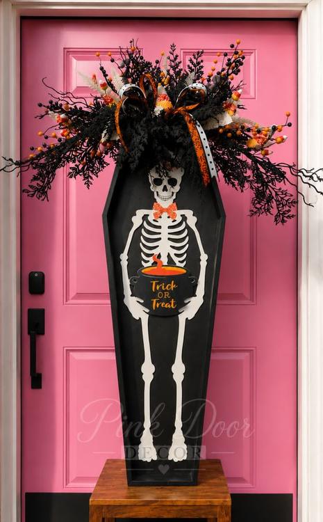 Tall black coffin door hanger with skeleton and candy corn spray on the pink door