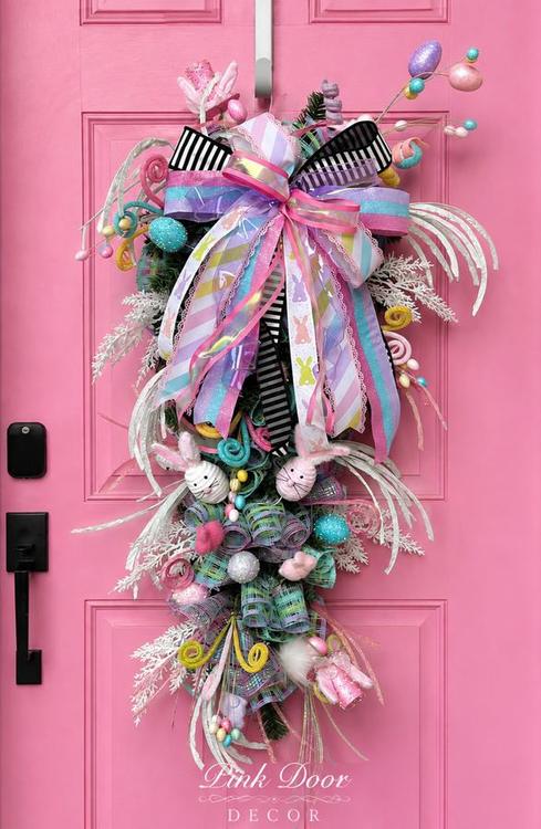 Pastel Easter swag with bunnies, glitter eggs, and striped bows on the pink door